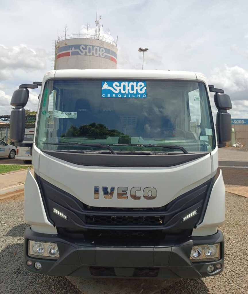 caminhão basculante branco visto de frente com adesivo na parte superior do para-brisas